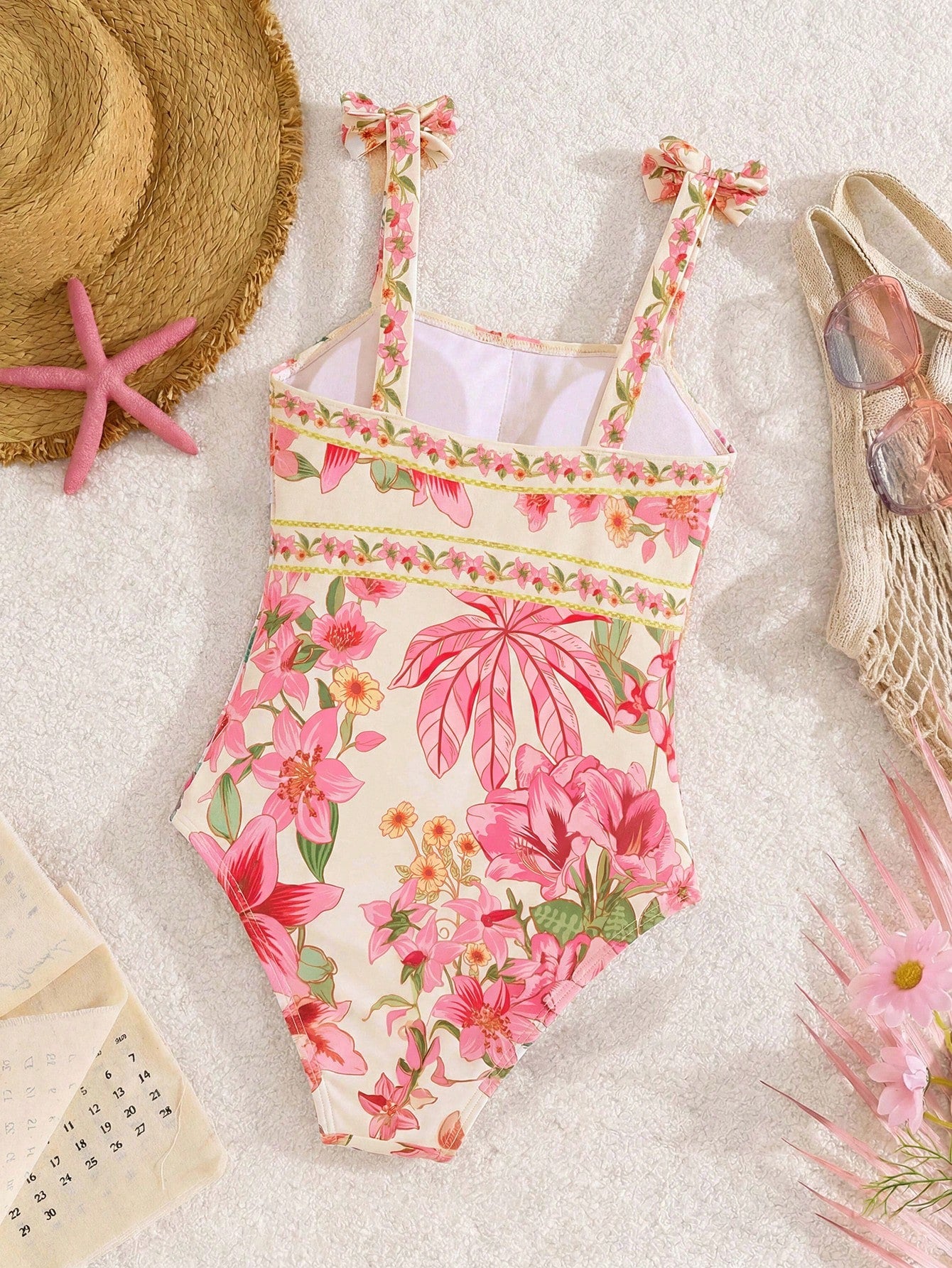 Tween girl floral print one-piece swimsuit with twist front, spaghetti straps, fitted shape, and multicolor all-over hibiscus-inspired pattern for beach and pool wear.