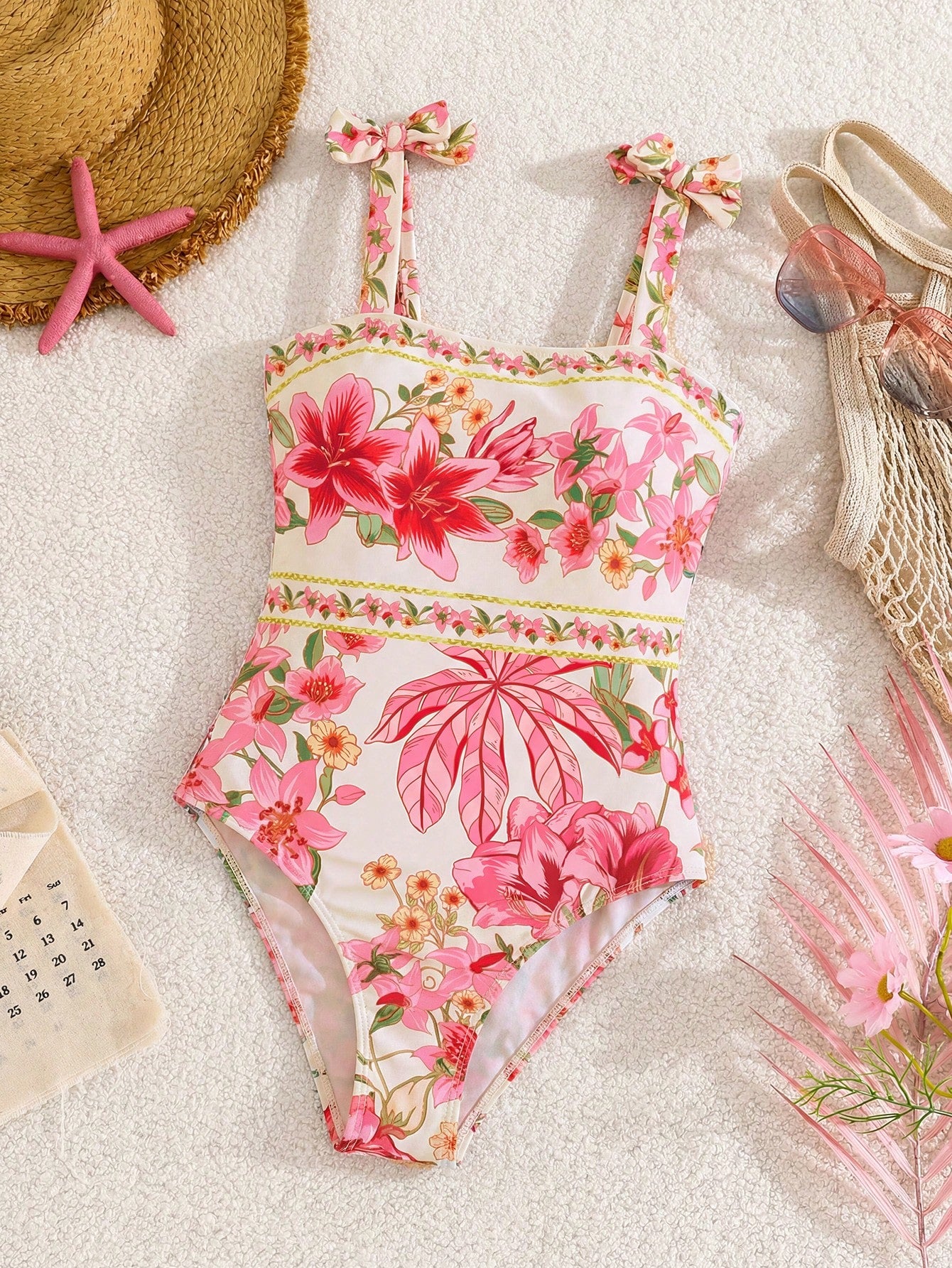 Tween girl floral print one-piece swimsuit with twist front, spaghetti straps, fitted shape, and multicolor all-over hibiscus-inspired pattern for beach and pool wear.