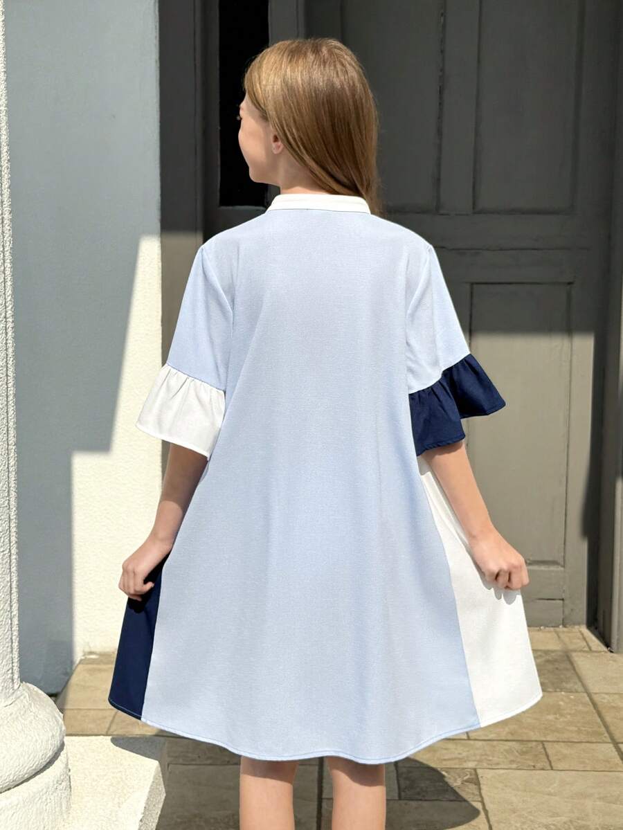 Tween girl wearing a black striped smock shirt dress with flounce half sleeves, a stand collar, and a ruffled hem.