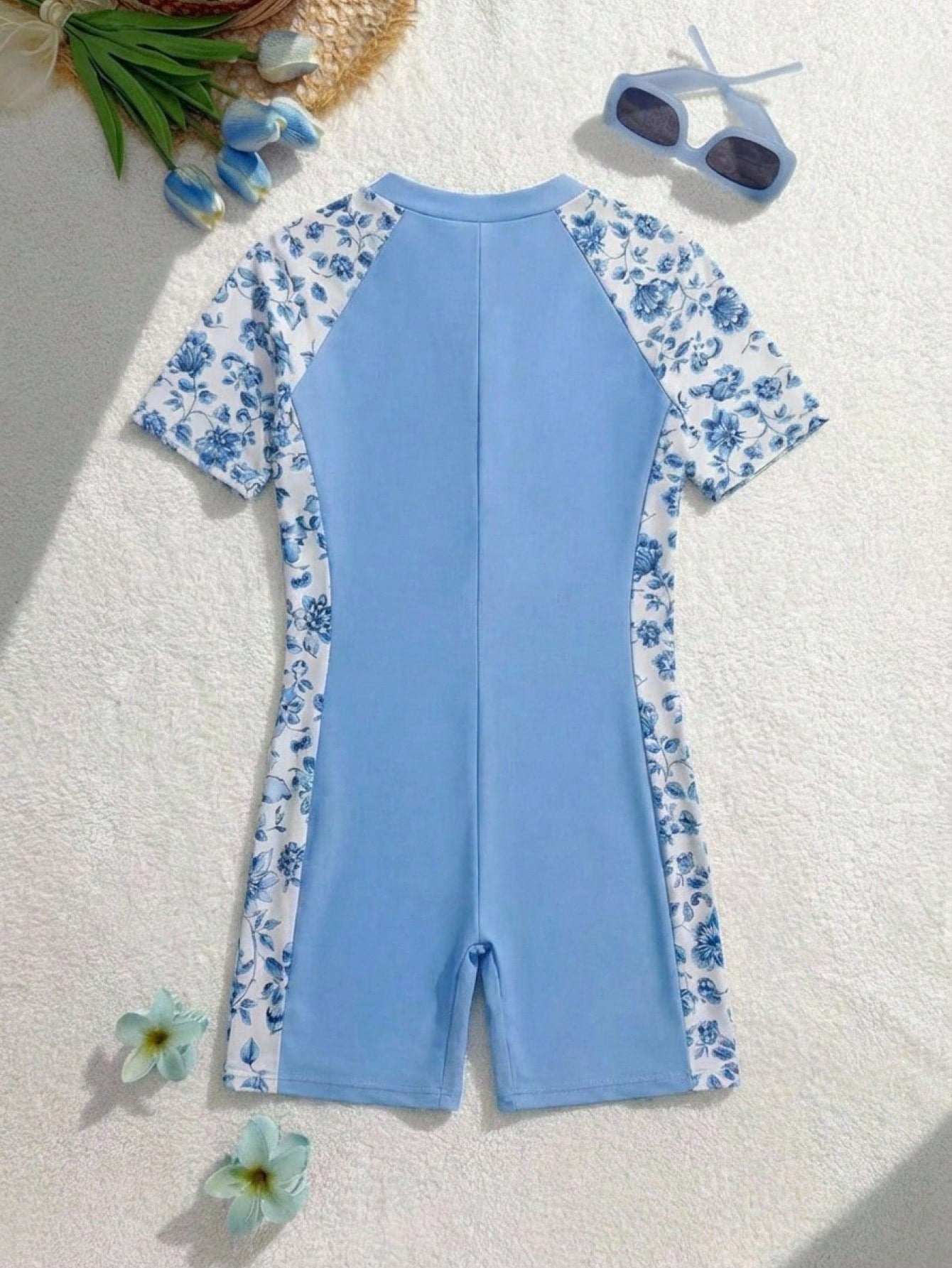 Black and white one-piece rashguard swimsuit for tween girls with short sleeves, high neck, zipper detail, fitted shape, and shorts-style bottom.