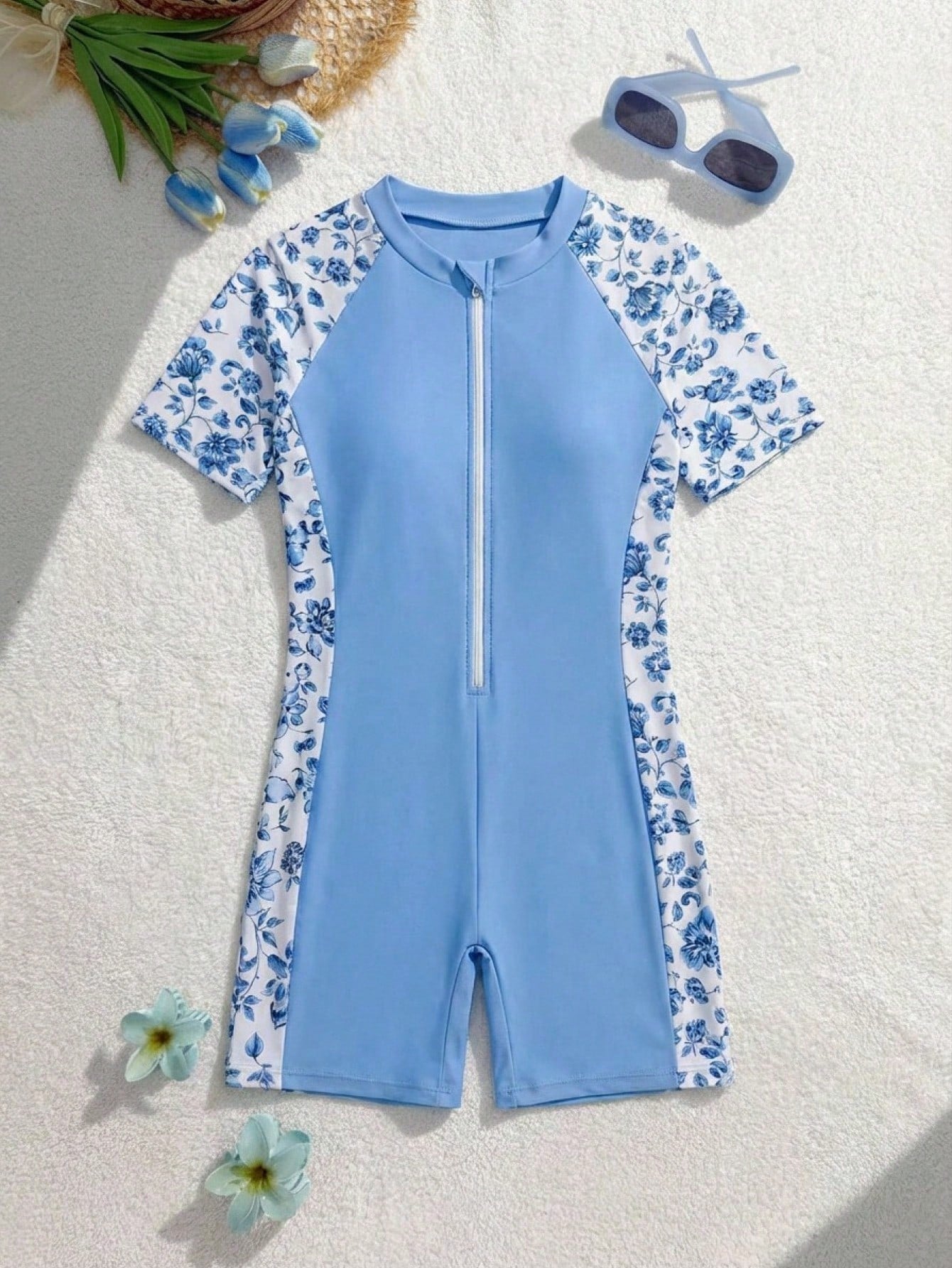 Black and white one-piece rashguard swimsuit for tween girls with short sleeves, high neck, zipper detail, fitted shape, and shorts-style bottom.