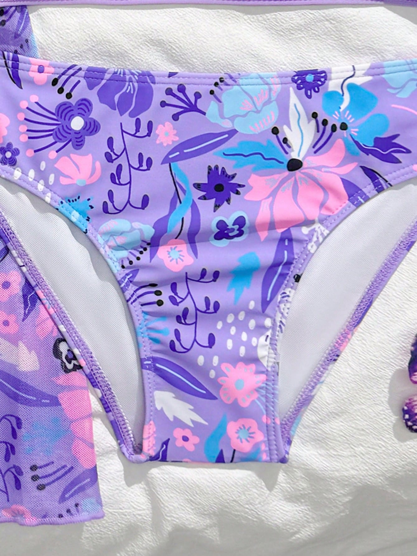 Three-piece tween girls swimwear set with a floral print, featuring a criss-cross bikini top, regular bikini bottoms, and a kimono cover-up in assorted prints.