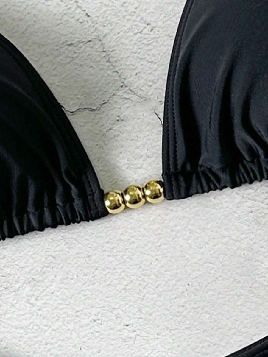 Women's black halter bikini set featuring triangle cups with gold bead decor and tie-back closure