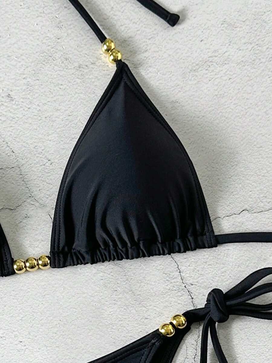 Women's black halter bikini set featuring triangle cups with gold bead decor and tie-back closure