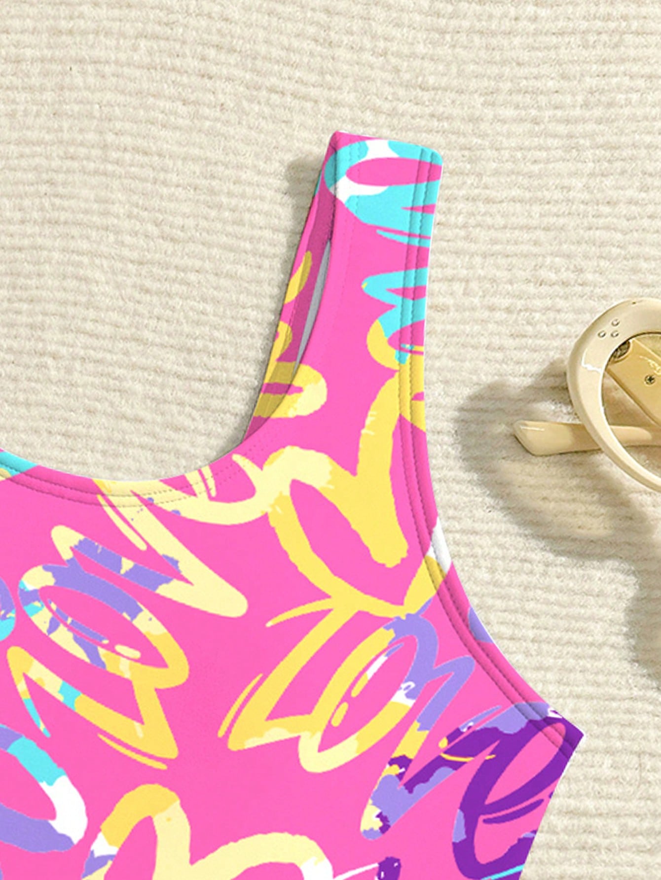 Baby pink girls one piece swimsuit with all over print, scoop neck, cut out detail, fitted shape, and lined body for tween beach and pool wear