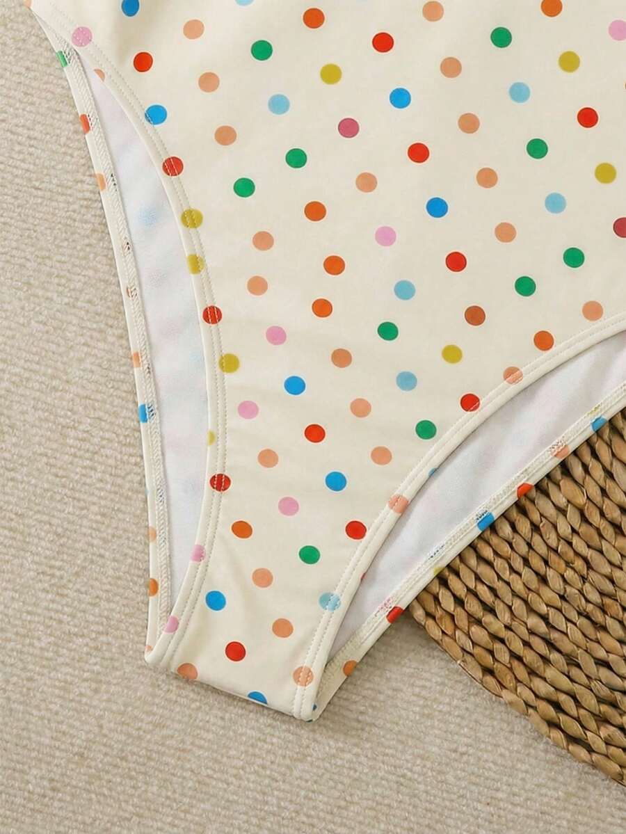 Women's apricot polka dot two-piece swimsuit featuring an asymmetrical halter backless top with knot tie detail and high-waisted bottoms.