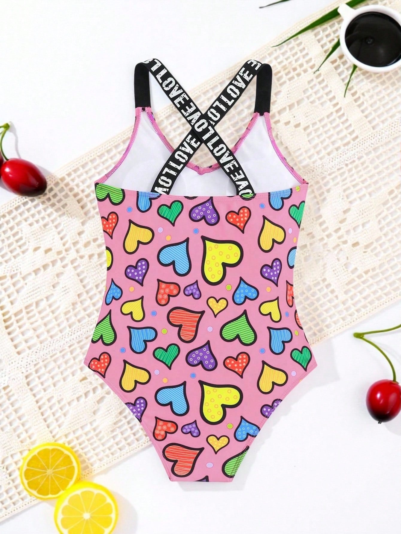 Baby pink girls one-piece swimsuit with ruffle detail, scoop neck, all-over print, and medium-stretch fabric for kids' beach and pool wear.