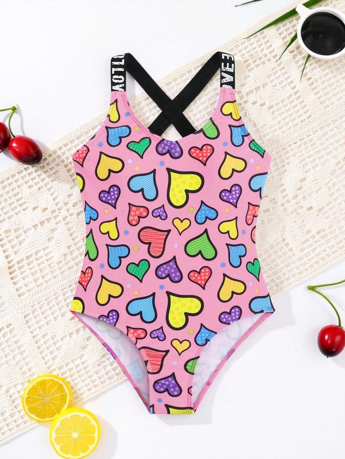 Baby pink girls one-piece swimsuit with ruffle detail, scoop neck, all-over print, and medium-stretch fabric for kids' beach and pool wear.