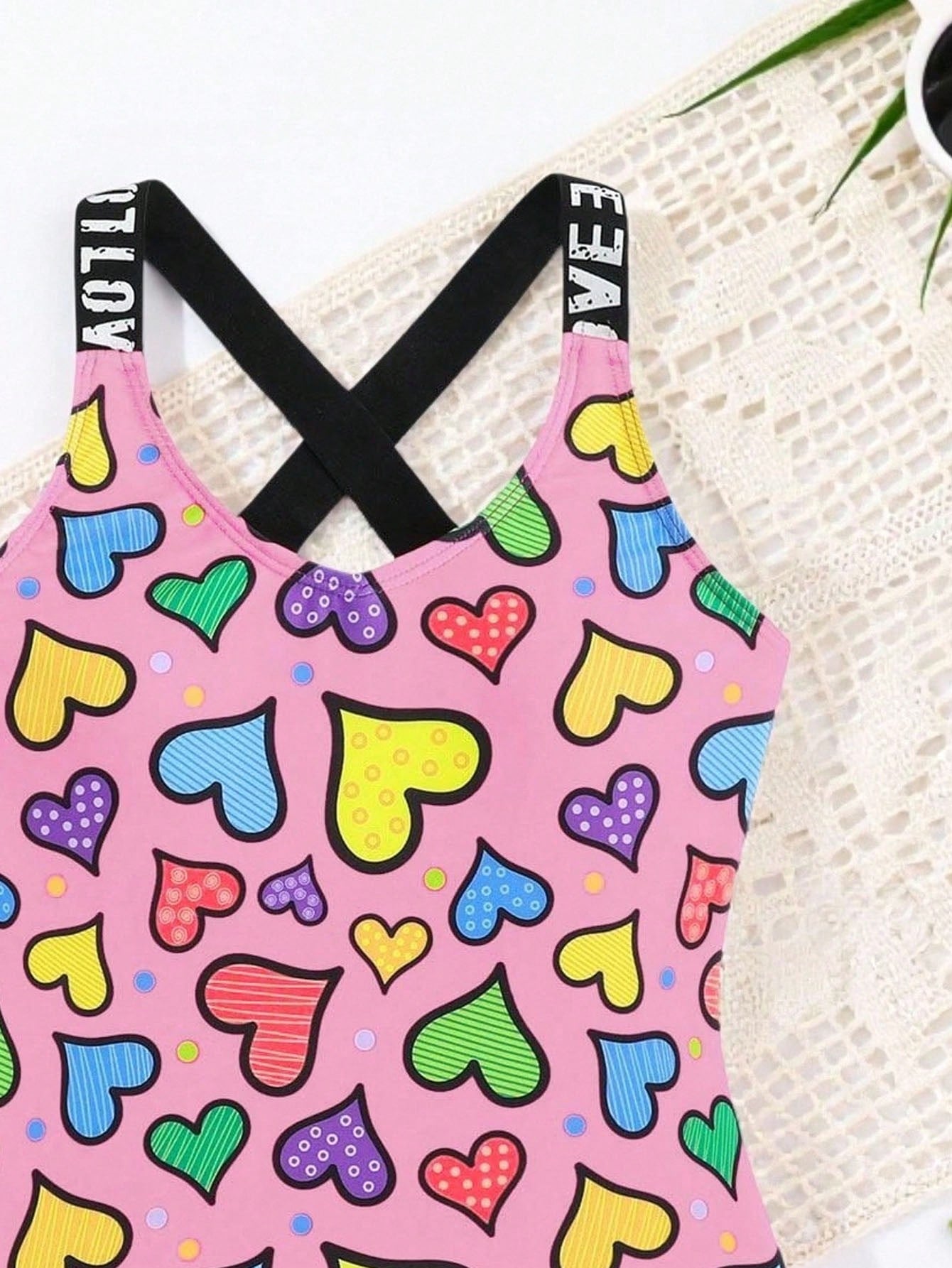 Baby pink girls one-piece swimsuit with ruffle detail, scoop neck, all-over print, and medium-stretch fabric for kids' beach and pool wear.