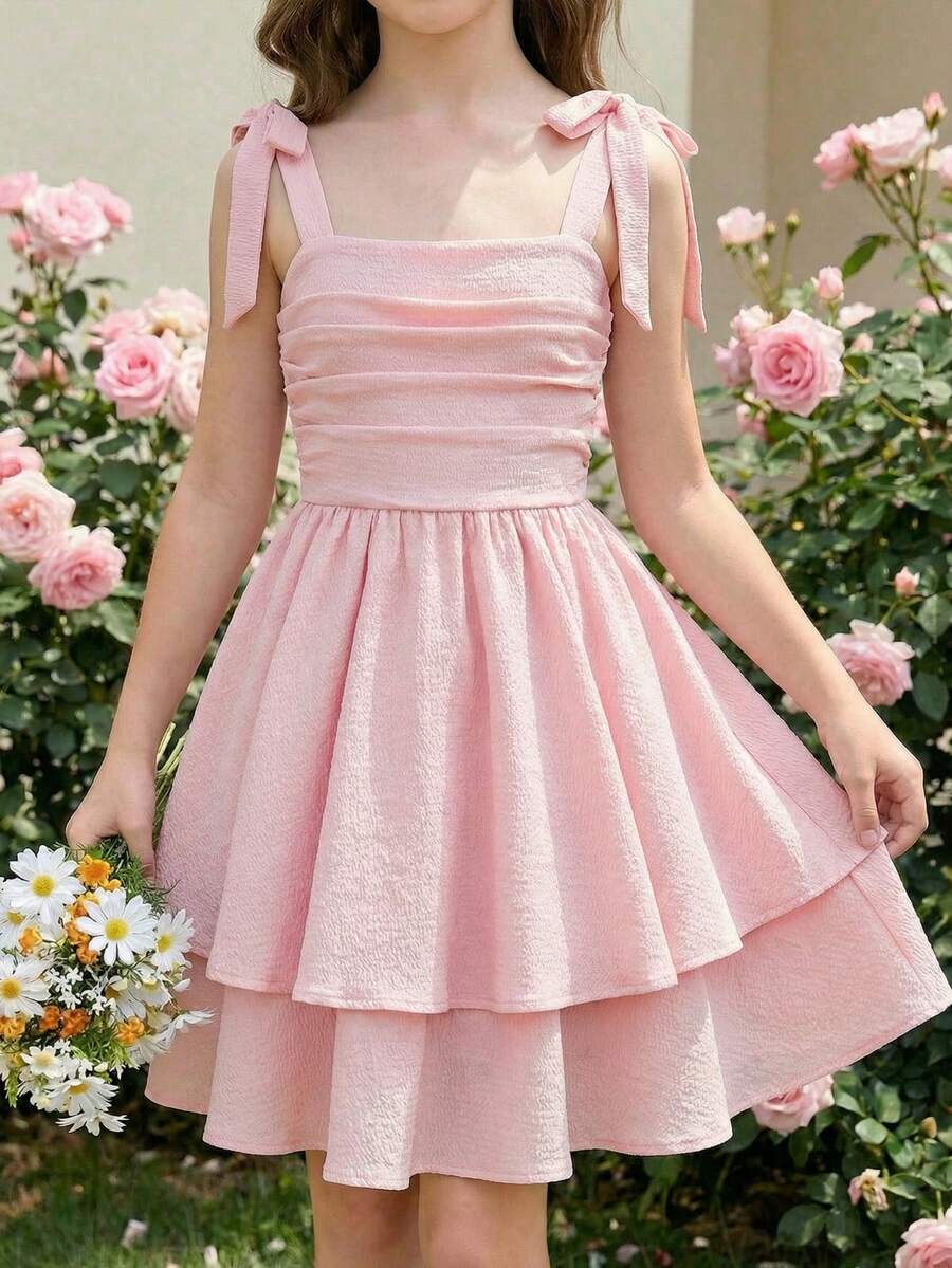 Tween girl wearing a pink tiered off-the-shoulder midi dress with shirred high waist and layered hem