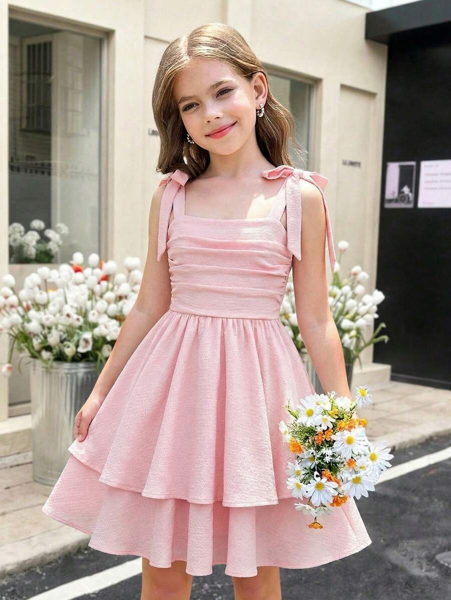 Tween girl wearing a pink tiered off-the-shoulder midi dress with shirred high waist and layered hem