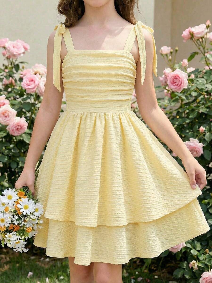 Tween girl wearing a pink tiered off-the-shoulder midi dress with shirred high waist and layered hem