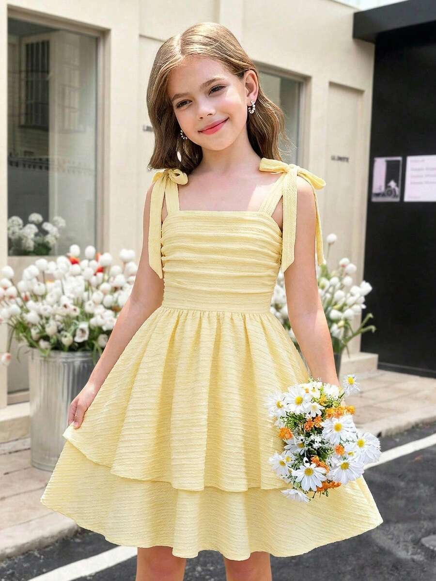 Tween girl wearing a pink tiered off-the-shoulder midi dress with shirred high waist and layered hem