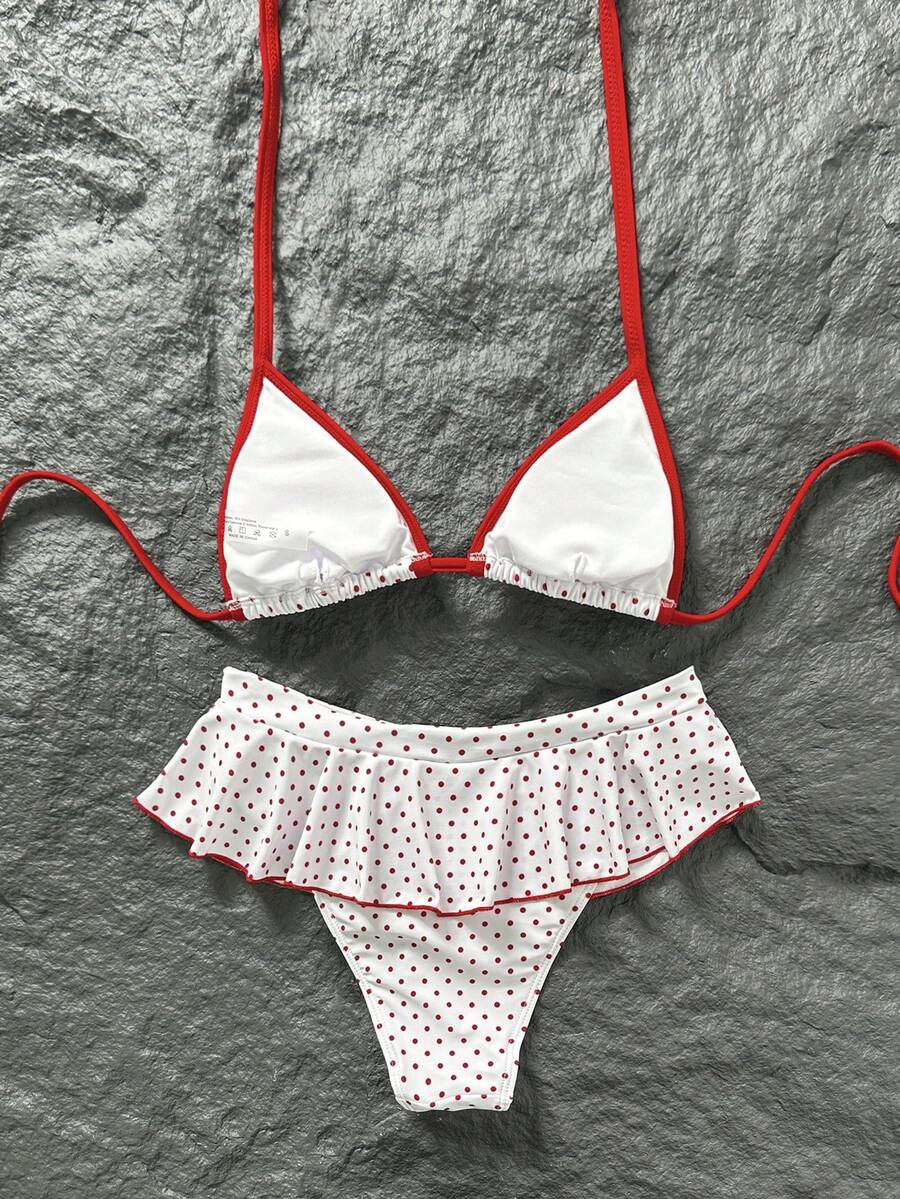 Women's 70s retro black and white polka dot bikini set featuring a halter triangle top and ultra low waist bottoms.