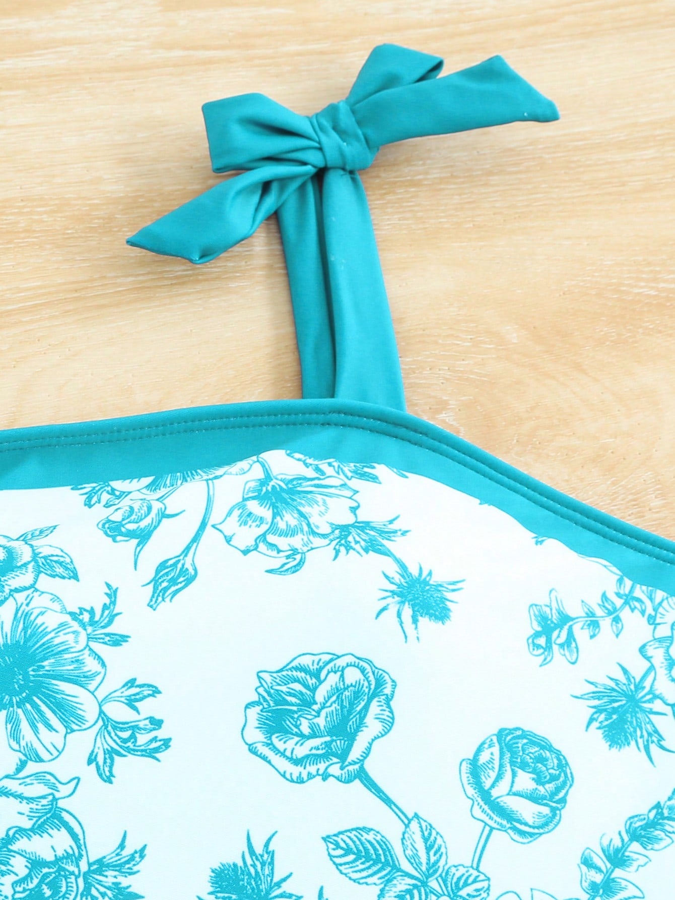 Tween girl black floral one-piece swimsuit set with spaghetti straps, asymmetrical detail, bow decor, and mid-waist bottom for beach, pool, and summer vacation wear.