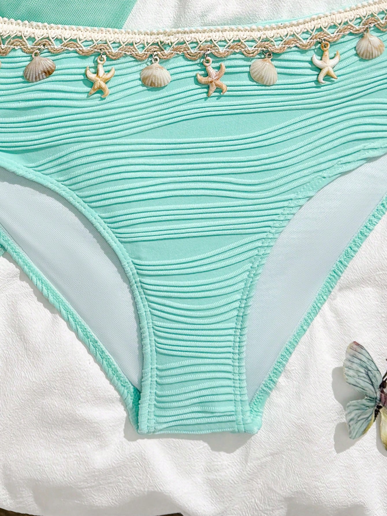 Tween girls bikini set with shell and starfish woven band details, spaghetti strap sleeveless top, and mid-waist skirt-style bottom in blue.