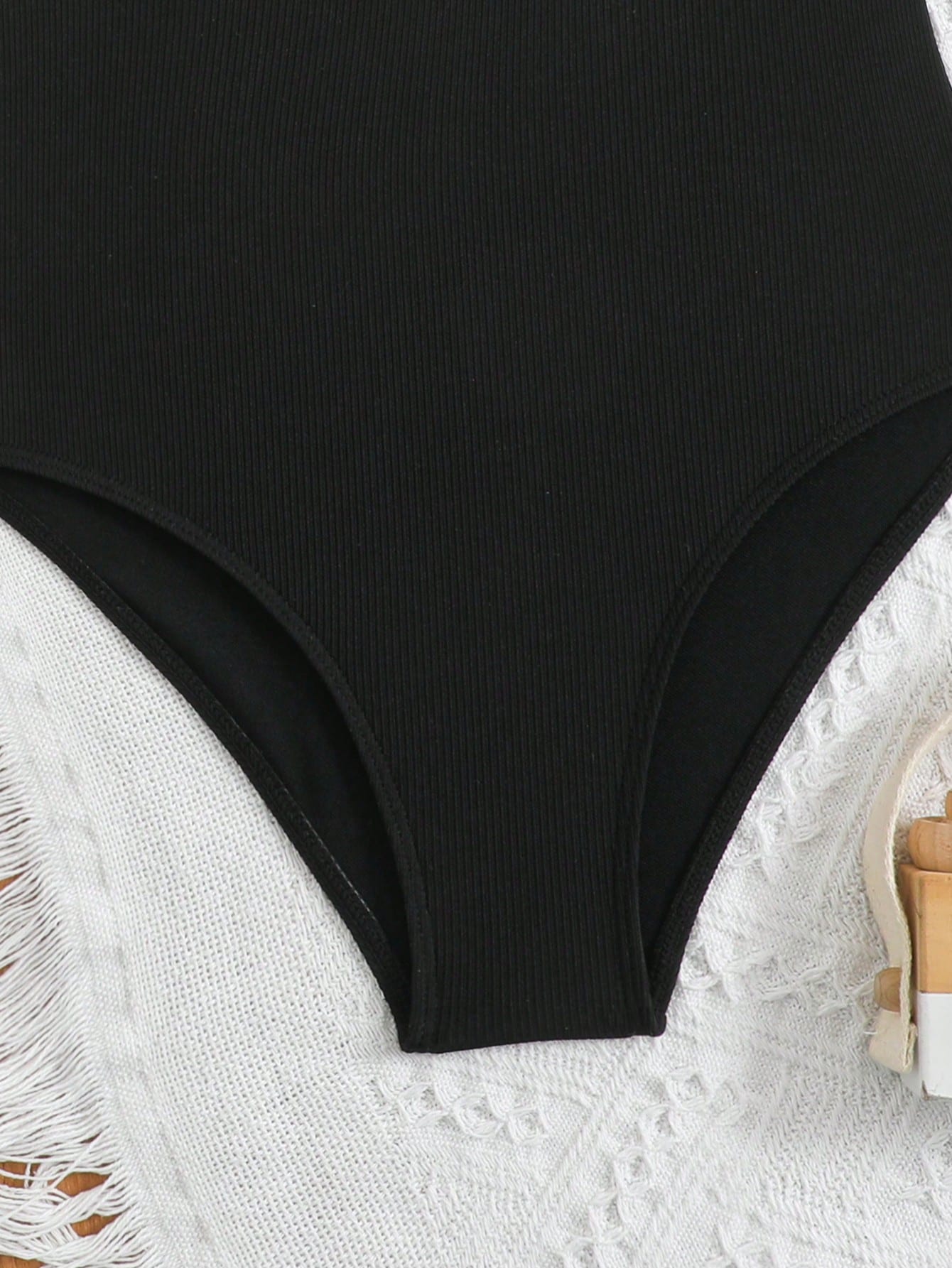 Black tween girls one-piece swimsuit with halter neckline, shell embroidery detail, ribbed texture, and mid-waist bottom for beach, swimming, and vacation wear.
