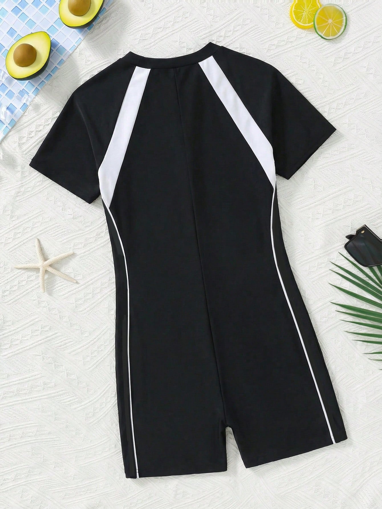 Black and white one-piece rashguard swimsuit for tween girls with short sleeves, high neck, zipper detail, fitted shape, and shorts-style bottom.