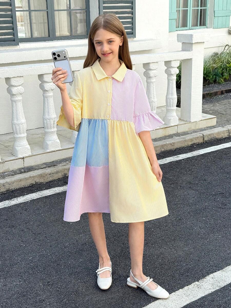 Tween girl wearing a black striped smock shirt dress with flounce half sleeves, a stand collar, and a ruffled hem.
