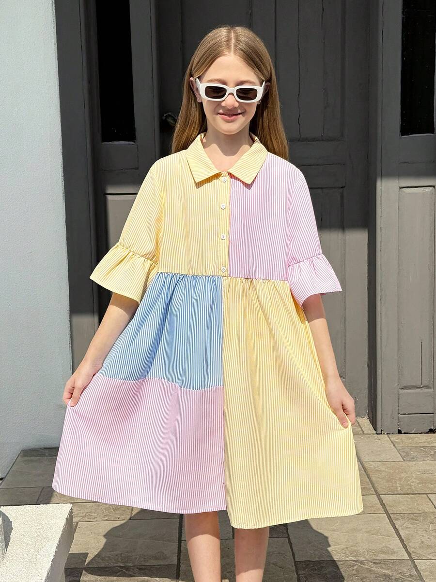 Tween girl wearing a black striped smock shirt dress with flounce half sleeves, a stand collar, and a ruffled hem.