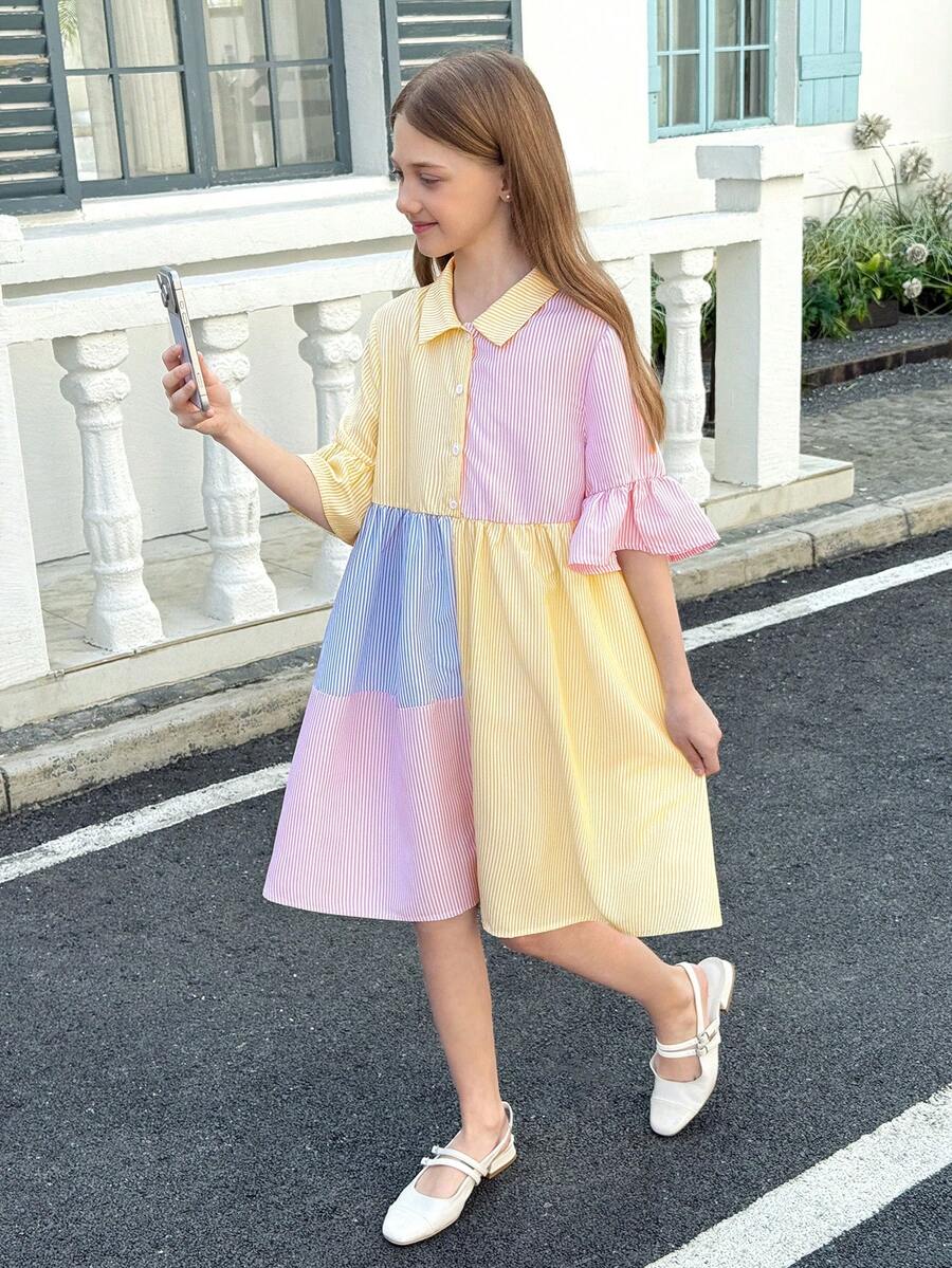 Tween girl wearing a black striped smock shirt dress with flounce half sleeves, a stand collar, and a ruffled hem.