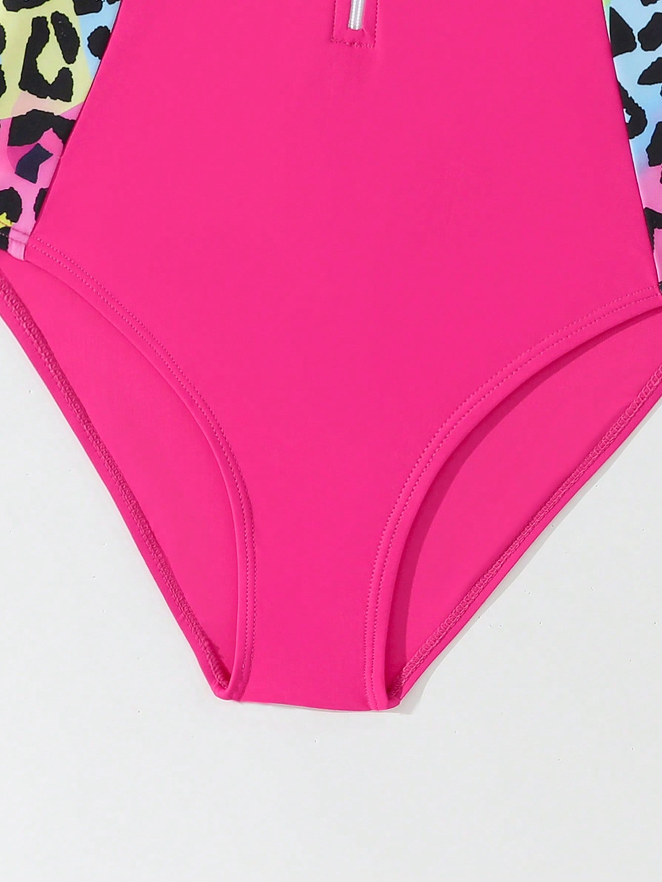 Girls one-piece swimsuit in blue with all-over leopard leaf print, ruffle detail, zipper front, high neck, and lined body for swimming and vacation.