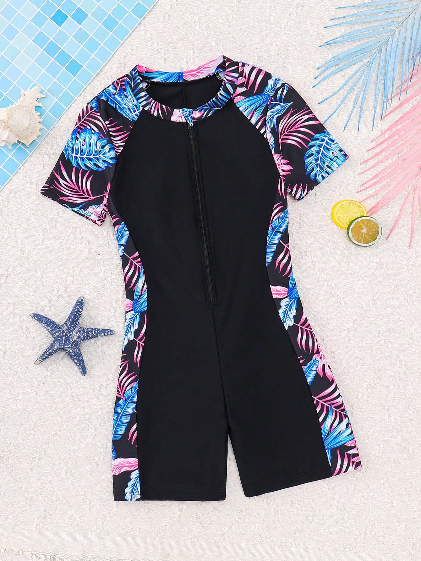 Black and white one-piece rashguard swimsuit for tween girls with short sleeves, high neck, zipper detail, fitted shape, and shorts-style bottom.