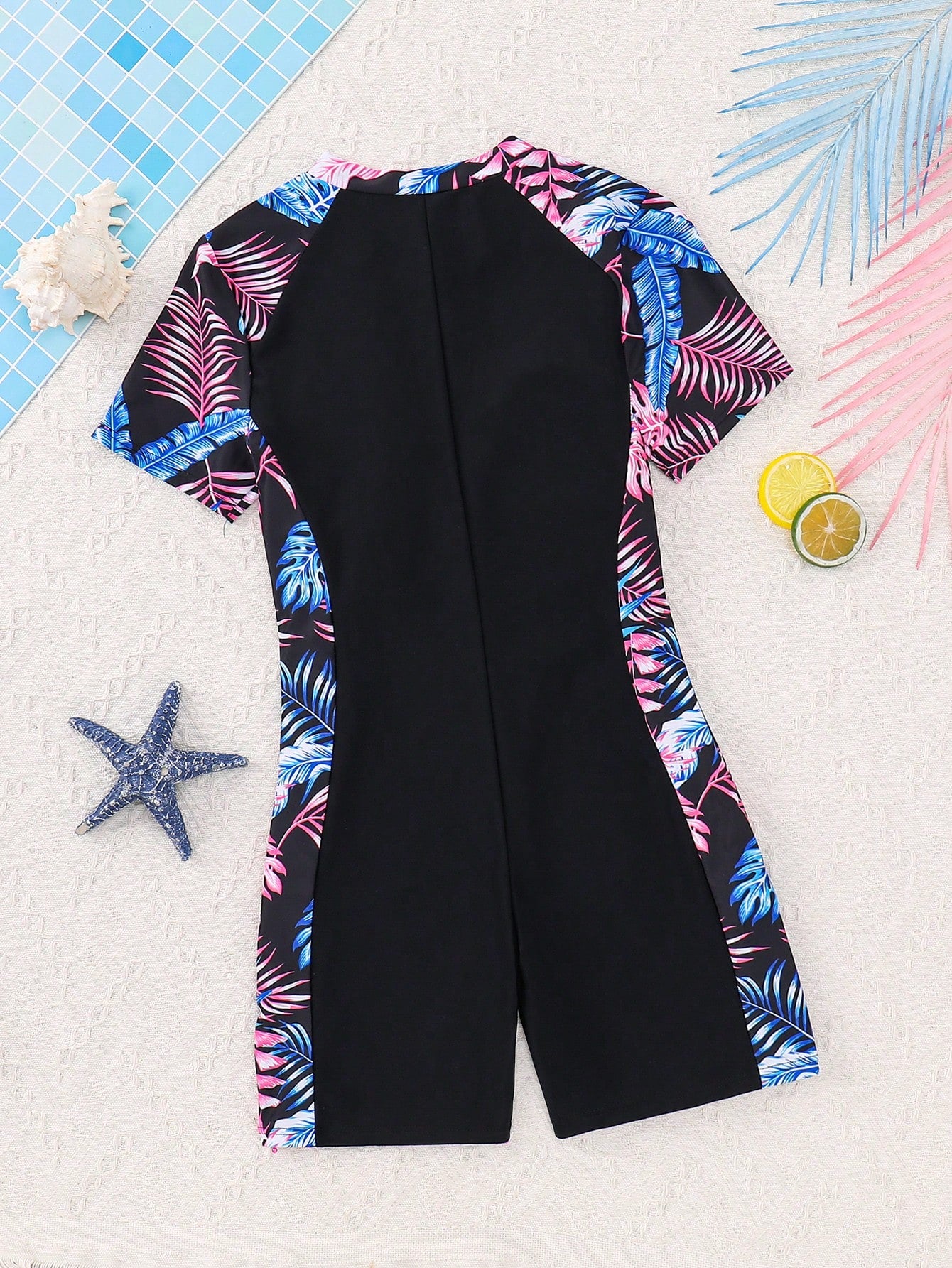 Black and white one-piece rashguard swimsuit for tween girls with short sleeves, high neck, zipper detail, fitted shape, and shorts-style bottom.