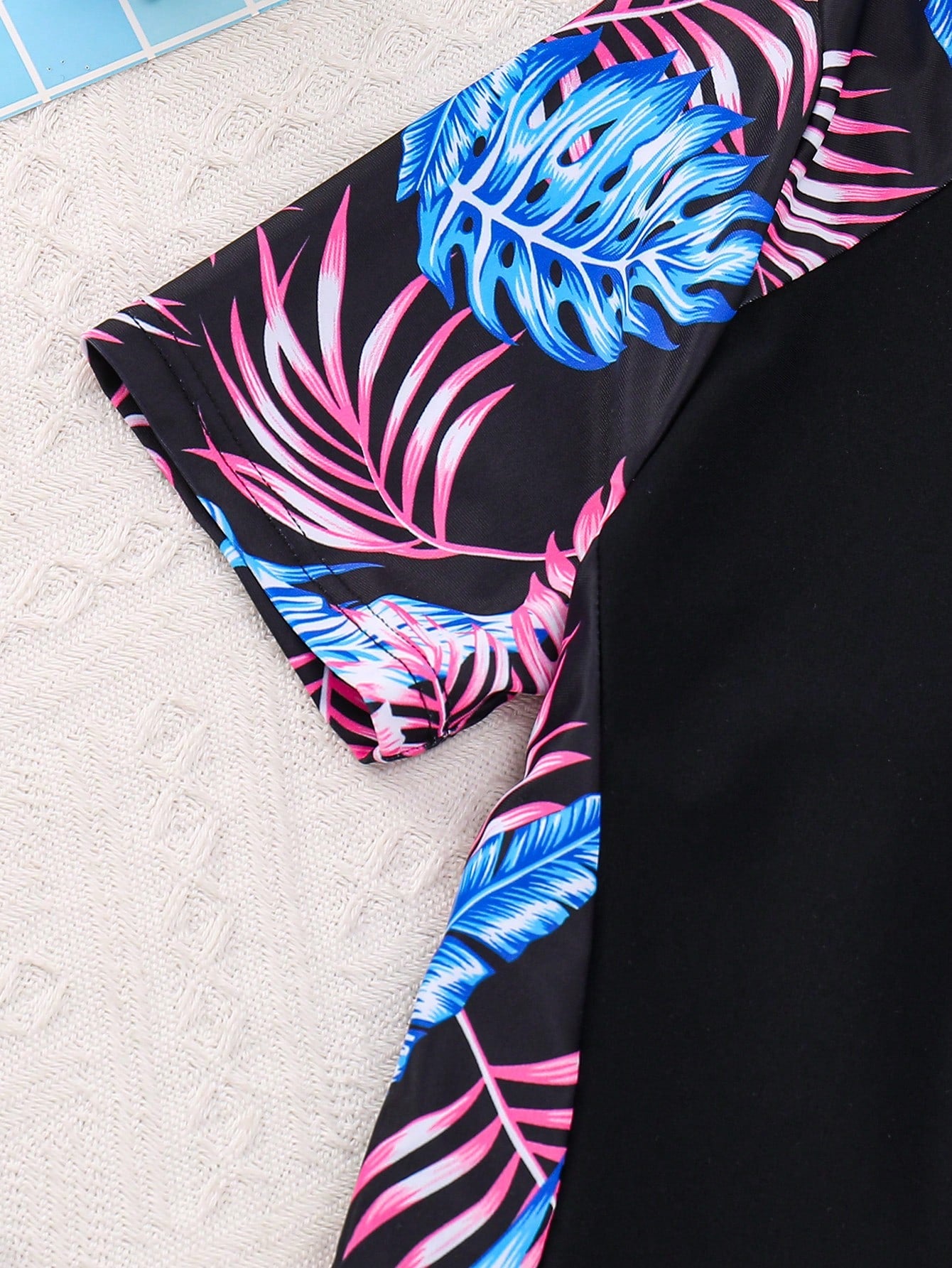 Black and white one-piece rashguard swimsuit for tween girls with short sleeves, high neck, zipper detail, fitted shape, and shorts-style bottom.