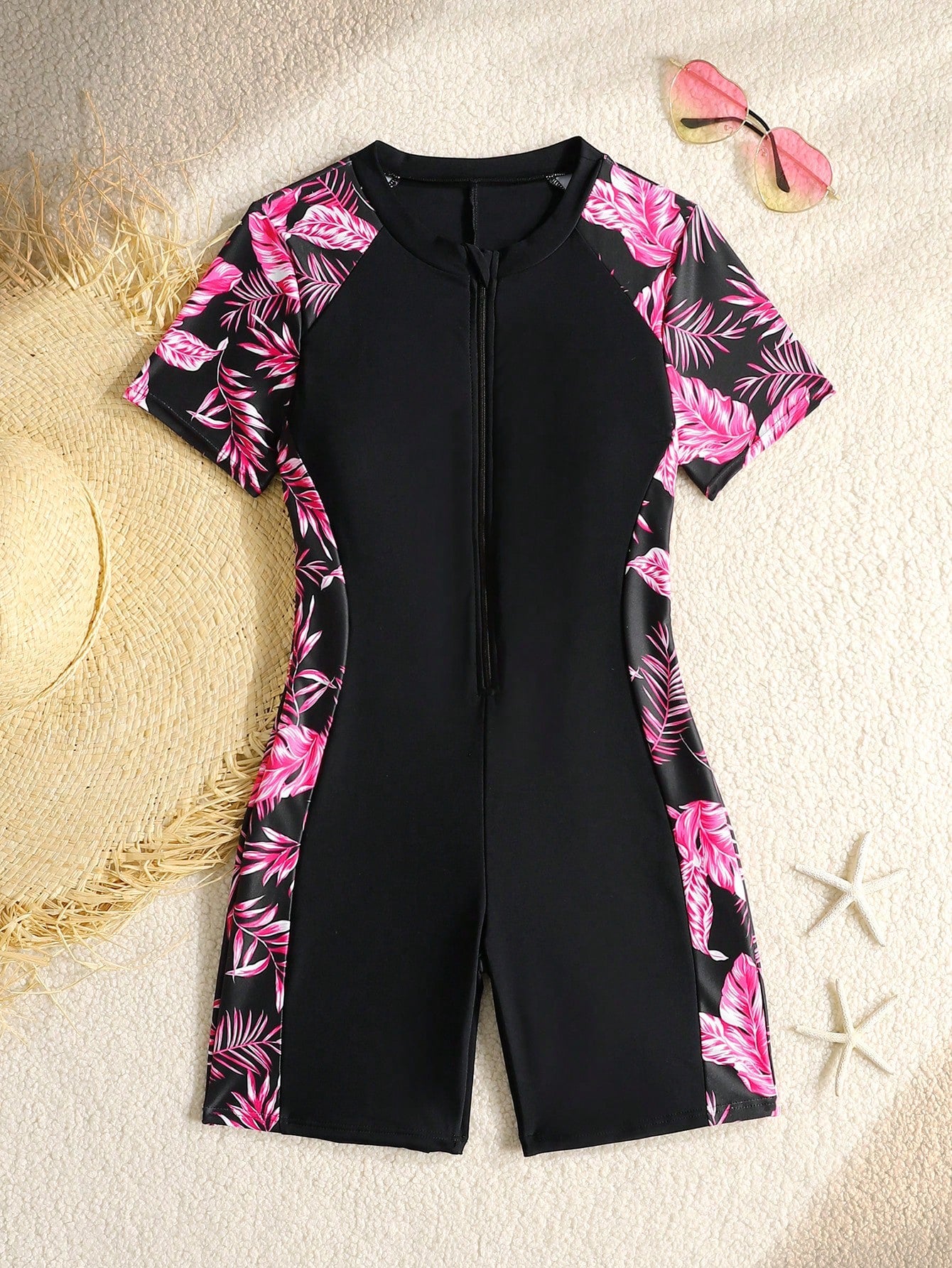 Black and white one-piece rashguard swimsuit for tween girls with short sleeves, high neck, zipper detail, fitted shape, and shorts-style bottom.