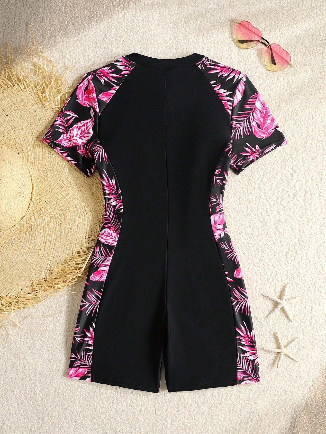 Black and white one-piece rashguard swimsuit for tween girls with short sleeves, high neck, zipper detail, fitted shape, and shorts-style bottom.