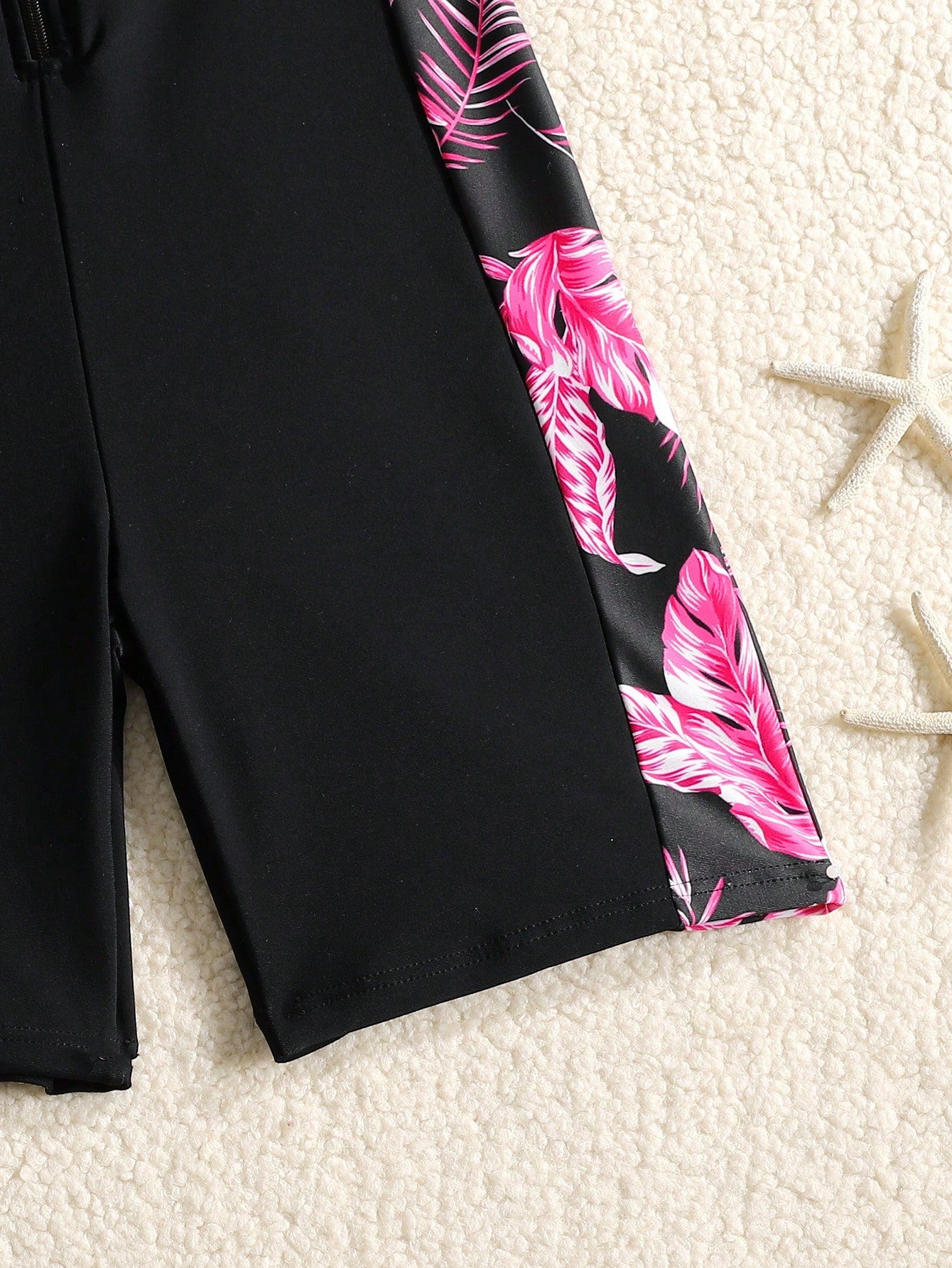 Black and white one-piece rashguard swimsuit for tween girls with short sleeves, high neck, zipper detail, fitted shape, and shorts-style bottom.