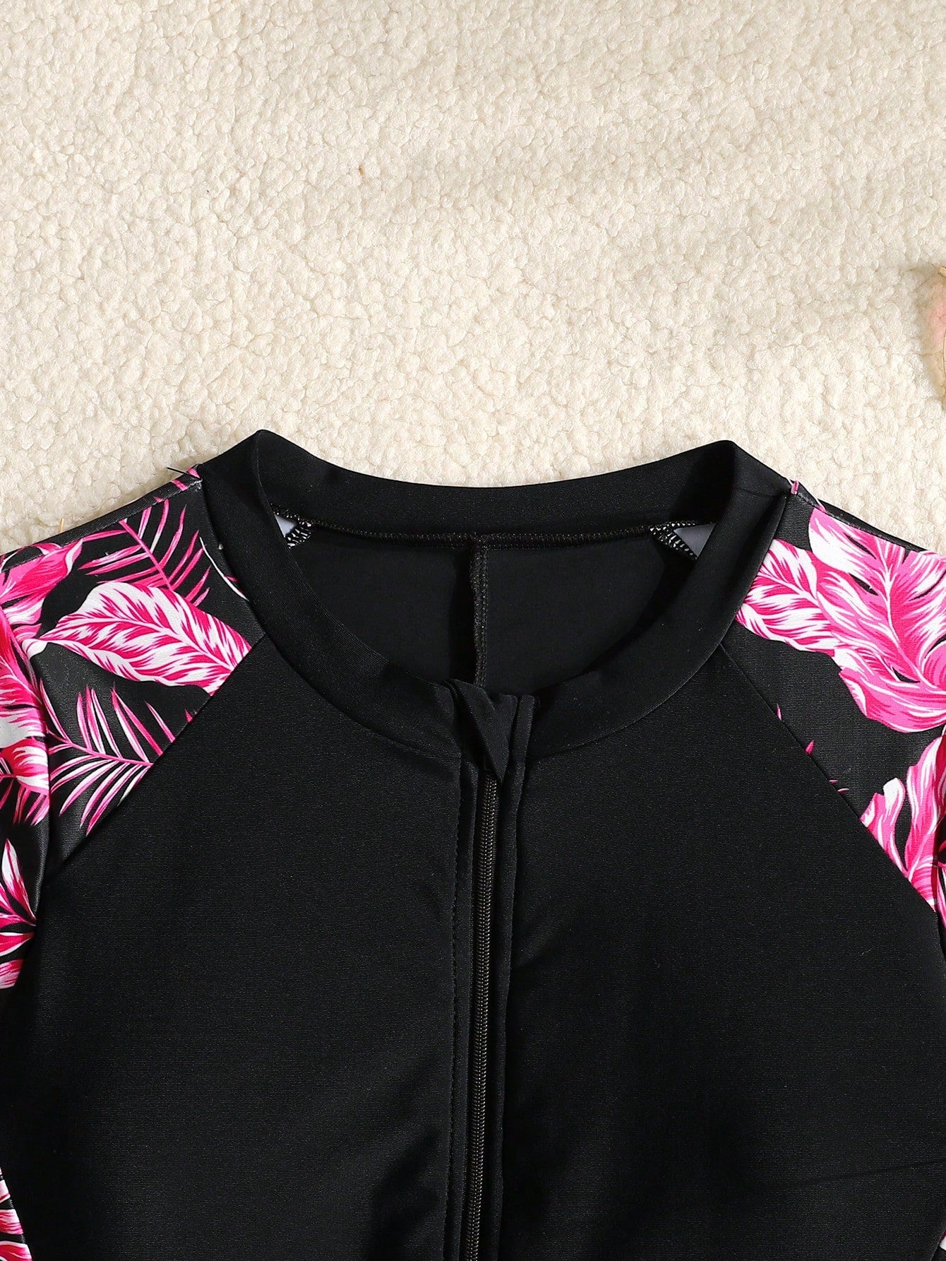 Black and white one-piece rashguard swimsuit for tween girls with short sleeves, high neck, zipper detail, fitted shape, and shorts-style bottom.