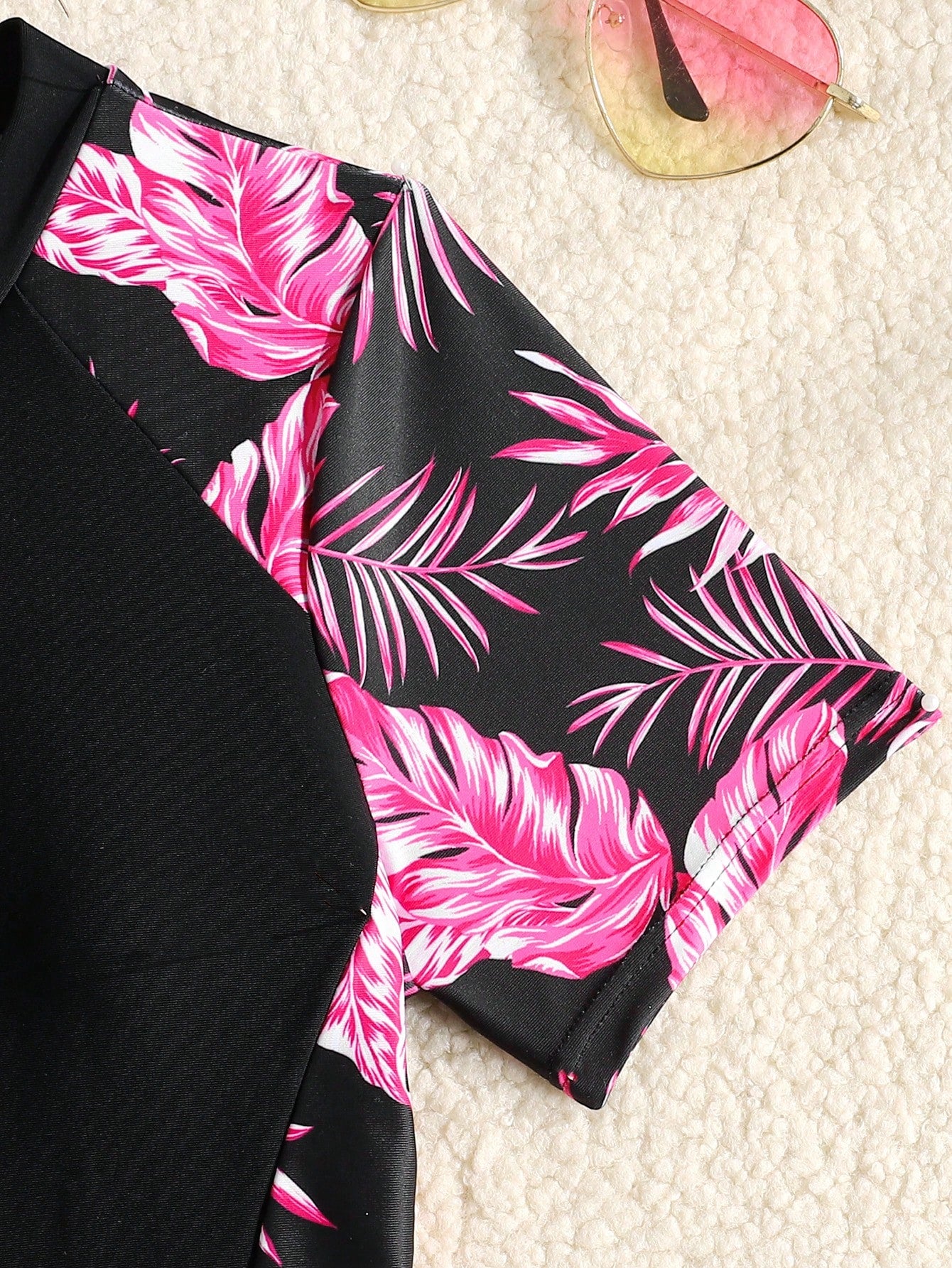 Black and white one-piece rashguard swimsuit for tween girls with short sleeves, high neck, zipper detail, fitted shape, and shorts-style bottom.