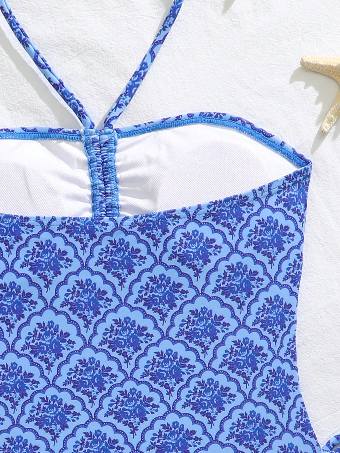 Blue halter one-piece swimsuit for tween girls with full geometric print, wireless bra design, mid-waist bottom, and medium-stretch fabric for beach and pool wear.