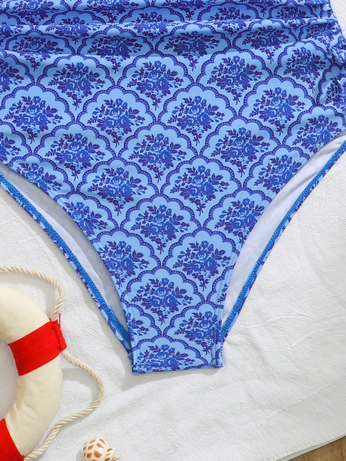 Blue halter one-piece swimsuit for tween girls with full geometric print, wireless bra design, mid-waist bottom, and medium-stretch fabric for beach and pool wear.
