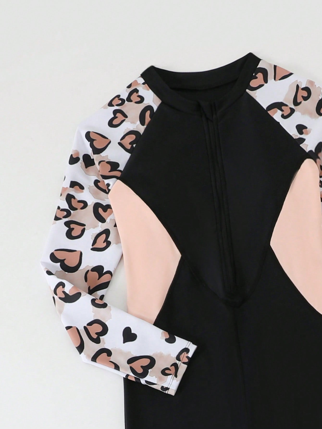 Tween girls black one-piece swimsuit with long sleeves, high neck, zipper detail, graphic leopard heart print, and fitted full-coverage swimwear style.