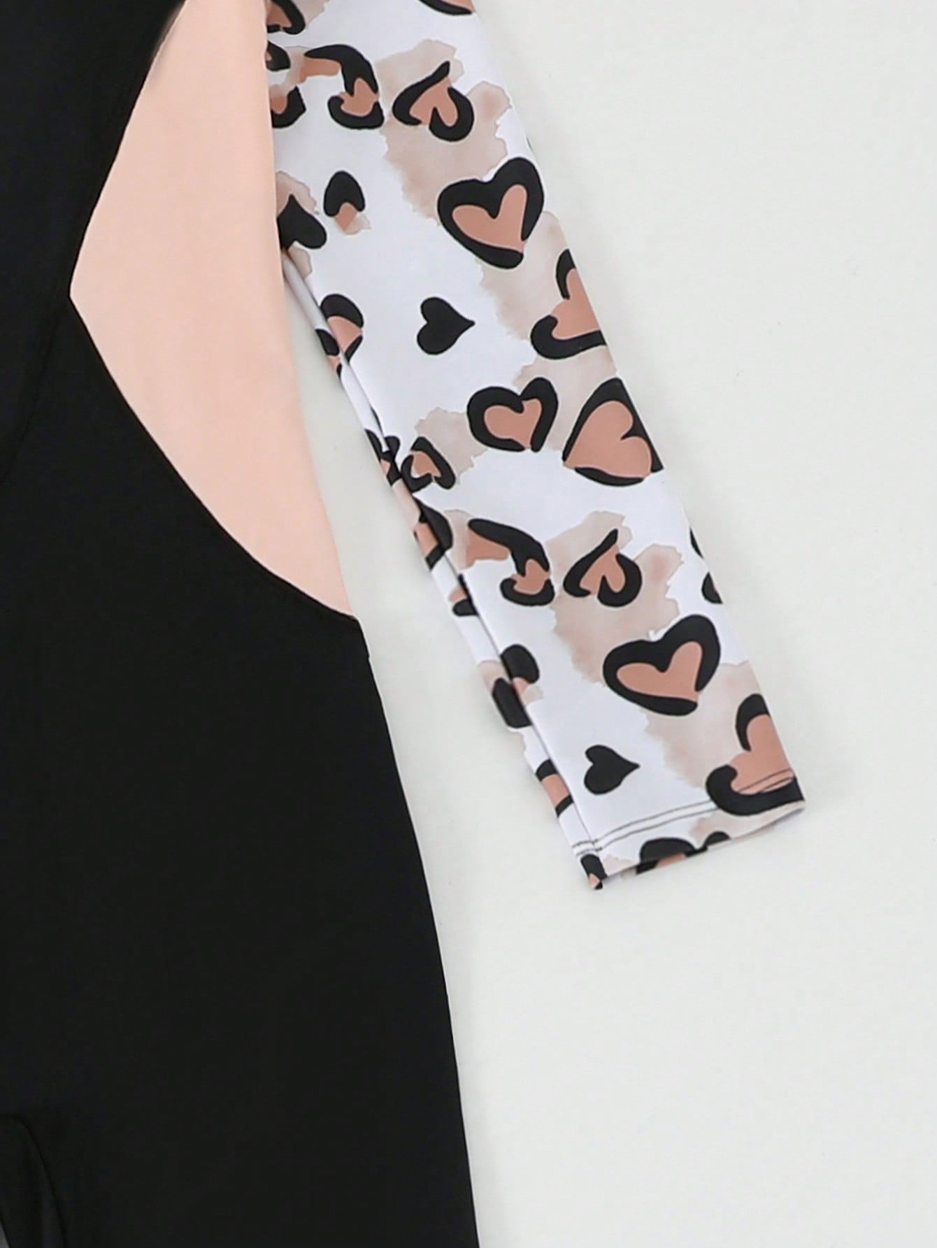 Tween girls black one-piece swimsuit with long sleeves, high neck, zipper detail, graphic leopard heart print, and fitted full-coverage swimwear style.