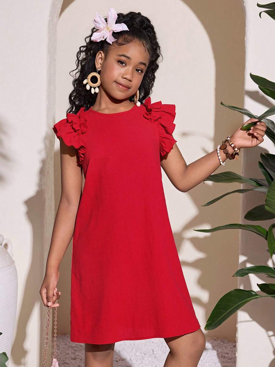 Tween girl wearing a blue ditsy floral patchwork tunic dress with ruffle button details and a round neckline.