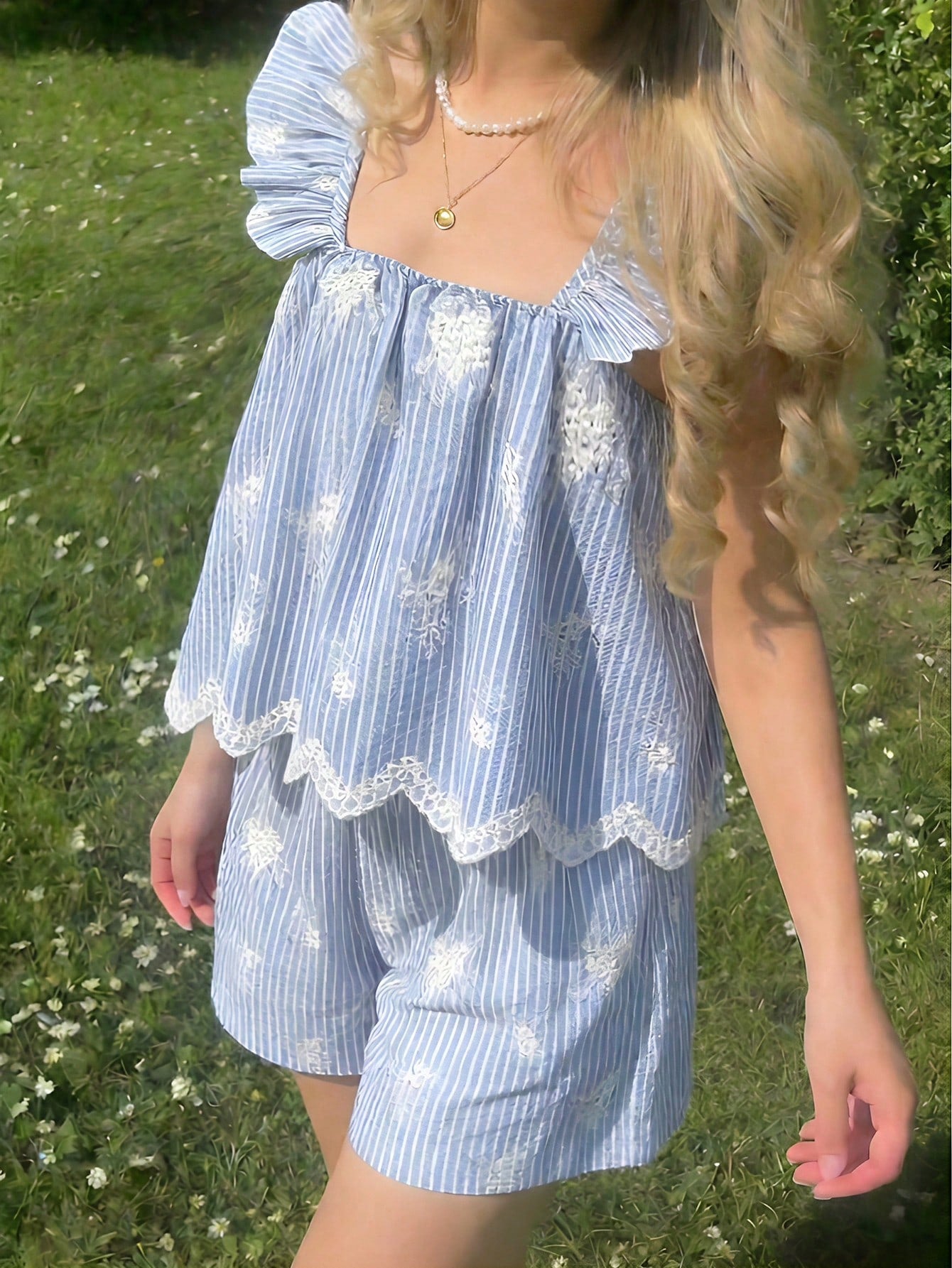 Tween girl wearing a blue and white striped sleeveless top featuring embroidery details and ruffle trim with matching shorts.