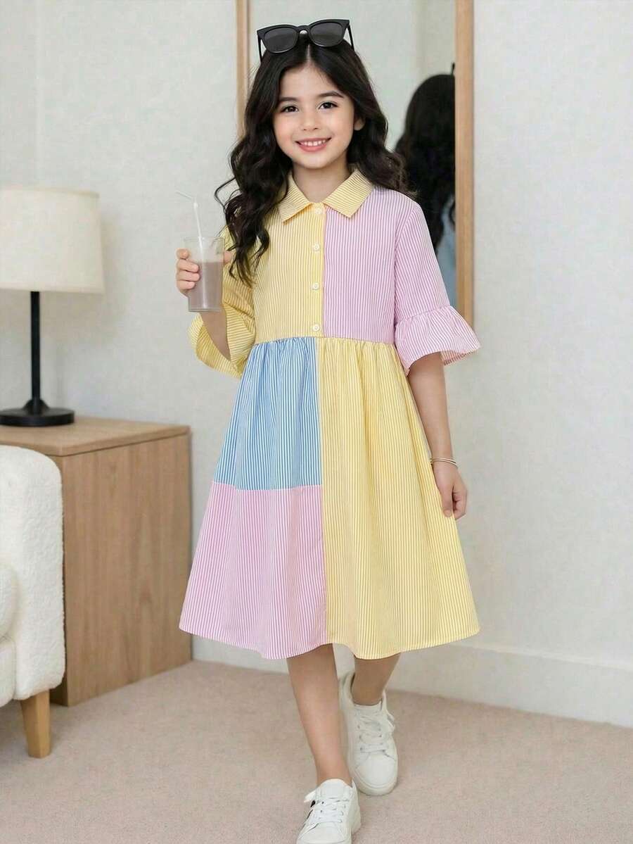 Tween girl wearing a black striped smock shirt dress with flounce half sleeves, a stand collar, and a ruffled hem.