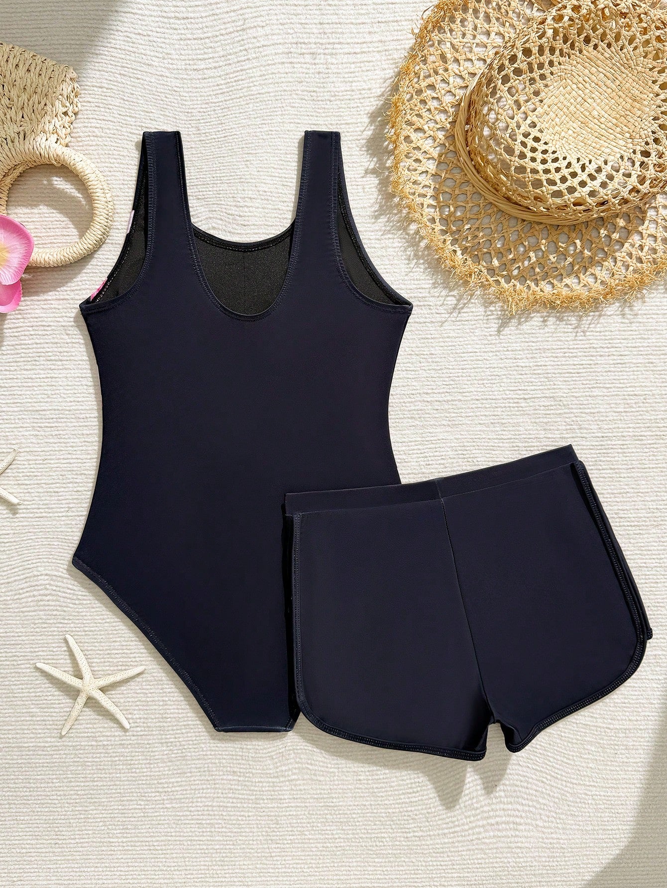 Tween girls 2-piece swimsuit set in black with full floral and plant print, featuring a sleeveless scoop-neck swim top and matching shorts-style bottoms.