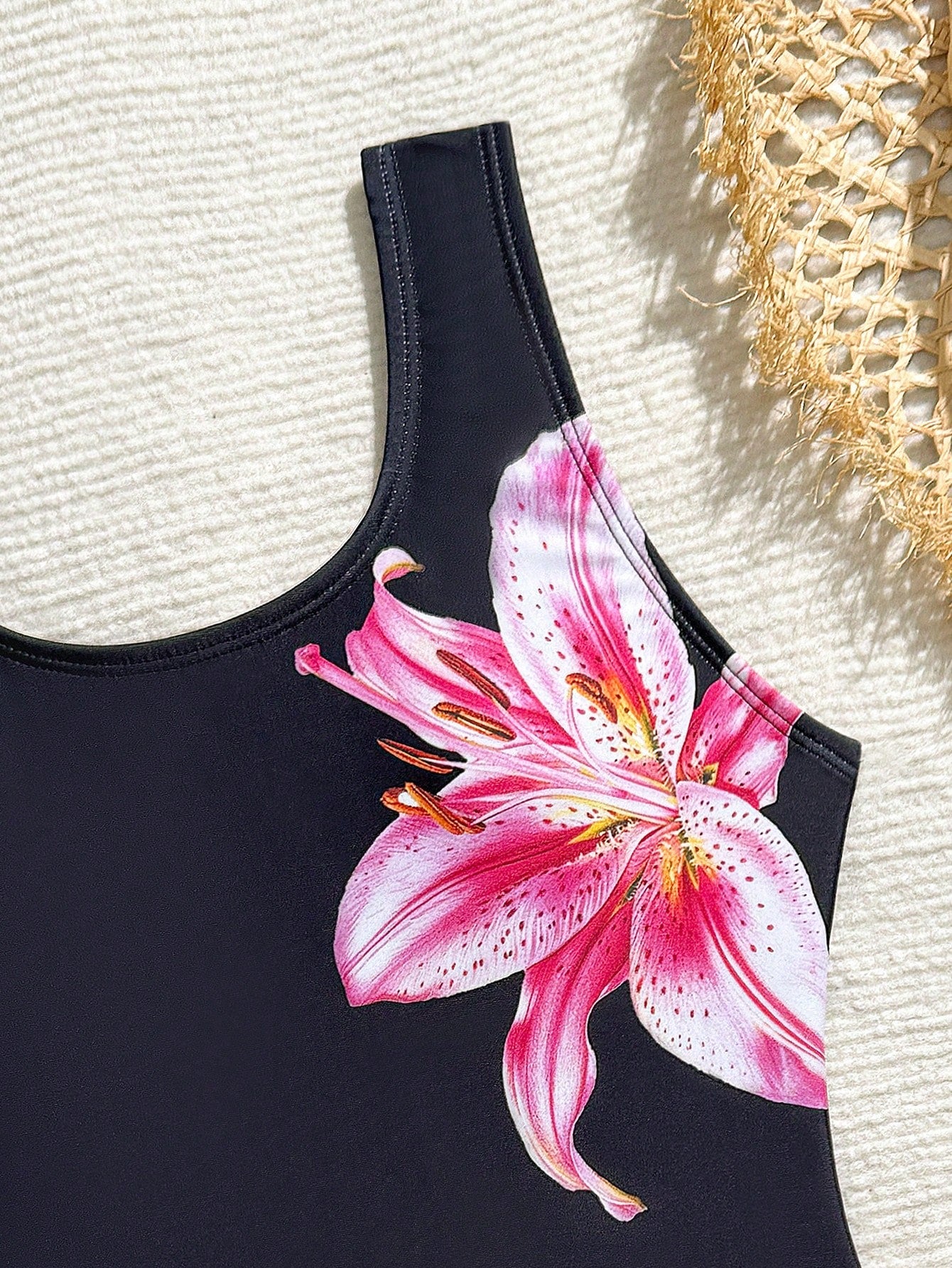 Tween girls 2-piece swimsuit set in black with full floral and plant print, featuring a sleeveless scoop-neck swim top and matching shorts-style bottoms.
