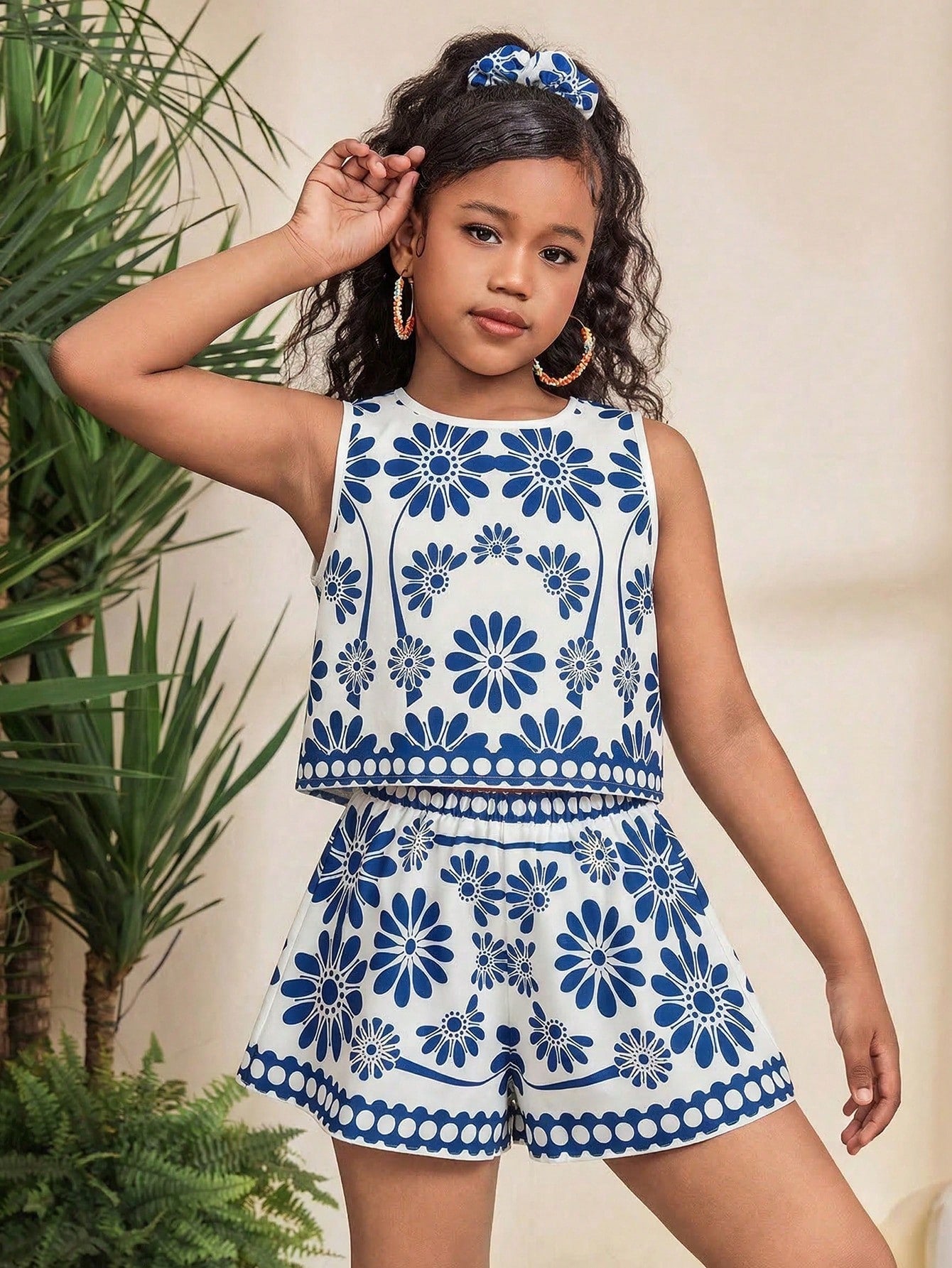 Tween girl wearing a tropical floral print two-piece vacation set featuring a sleeveless round neck tank top with button details and matching shorts.