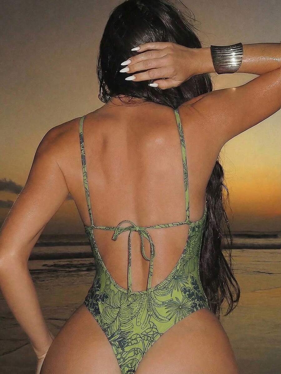 Women's black lace one-piece swimsuit featuring a deep V-neckline, spaghetti straps, backless tie-up detail, and thong bottom.