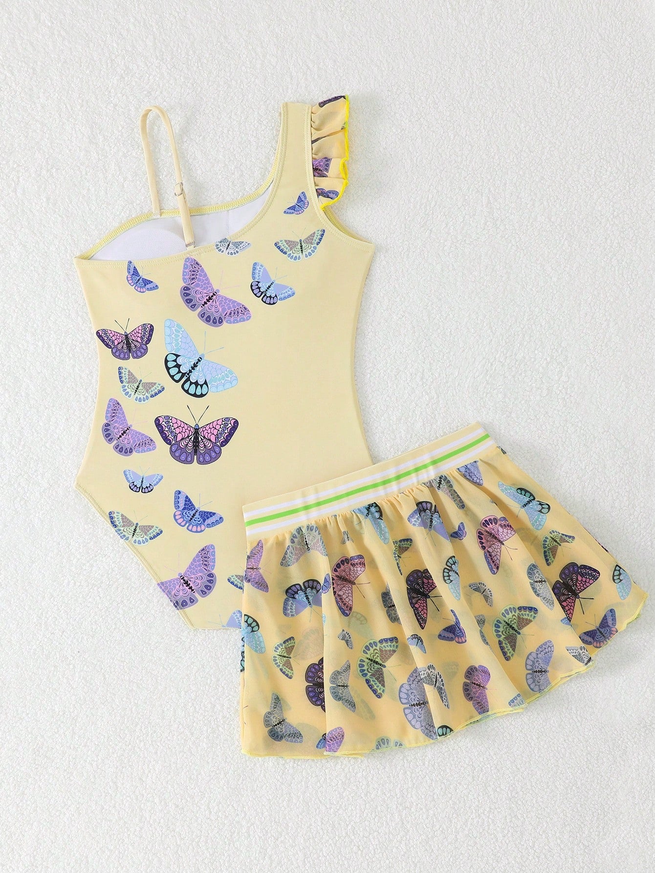 Girls yellow one-piece swimsuit with asymmetrical neckline, ruffle detail, sleeveless fitted style, and skirt bottom for beach and pool vacations.