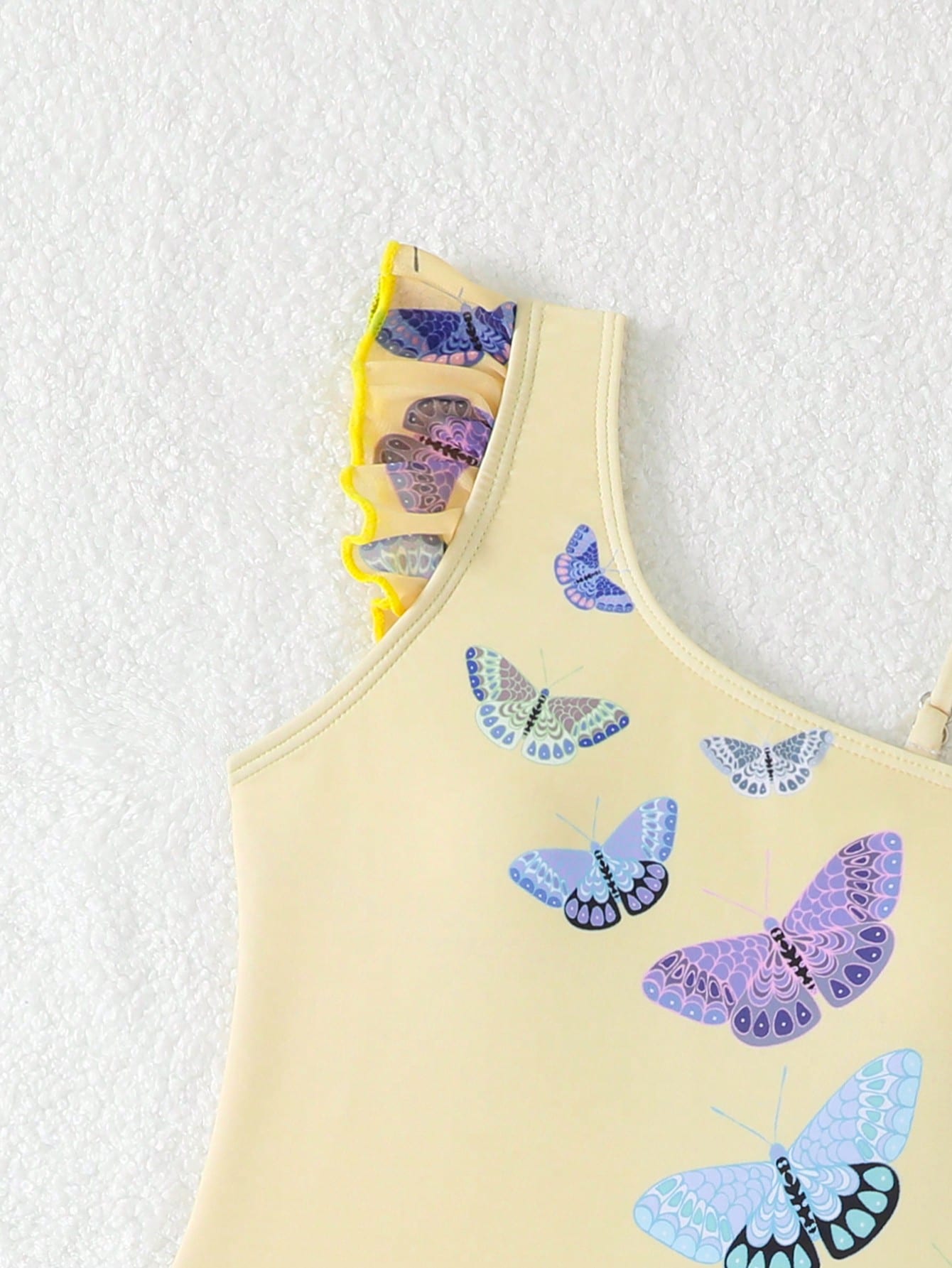 Girls yellow one-piece swimsuit with asymmetrical neckline, ruffle detail, sleeveless fitted style, and skirt bottom for beach and pool vacations.