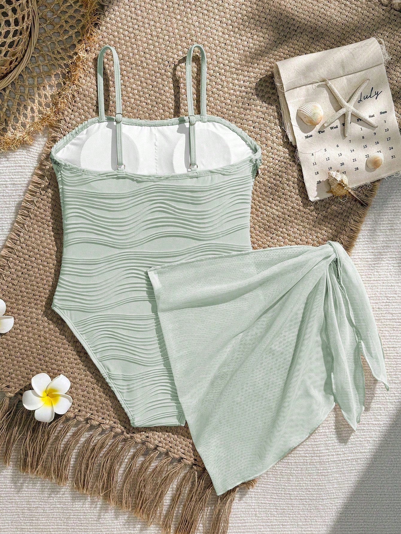 Blue girls one-piece swimsuit with spaghetti straps, textured plain fabric, shell-inspired detail, and matching skirt bottom for beach or pool vacation wear.