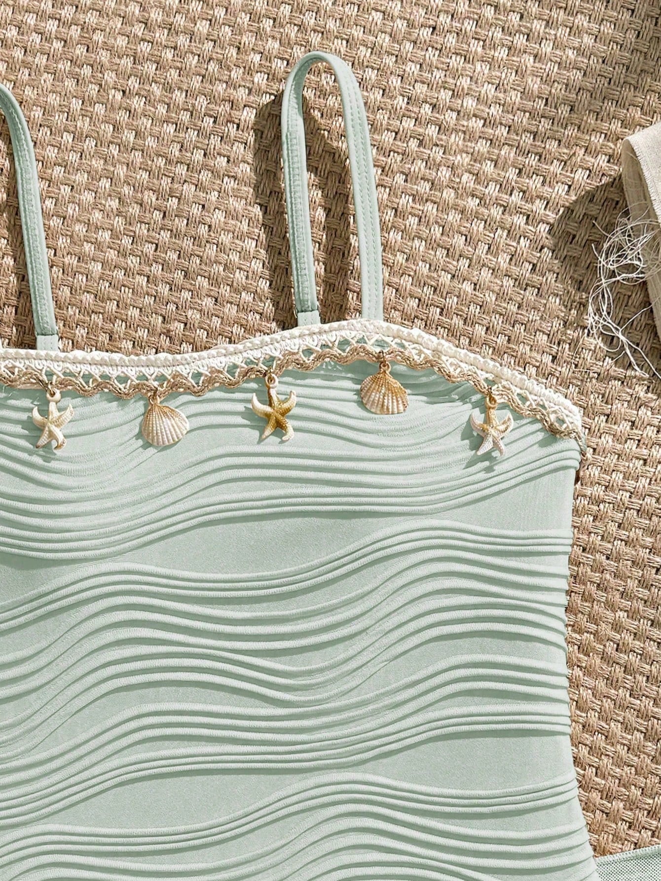 Blue girls one-piece swimsuit with spaghetti straps, textured plain fabric, shell-inspired detail, and matching skirt bottom for beach or pool vacation wear.