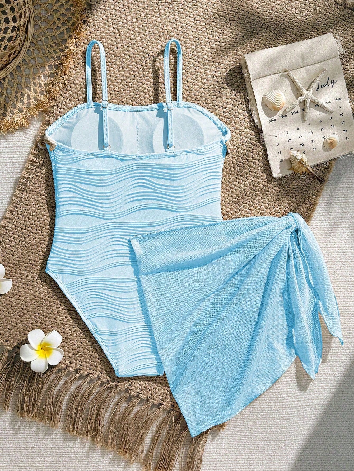 Blue girls one-piece swimsuit with spaghetti straps, textured plain fabric, shell-inspired detail, and matching skirt bottom for beach or pool vacation wear.
